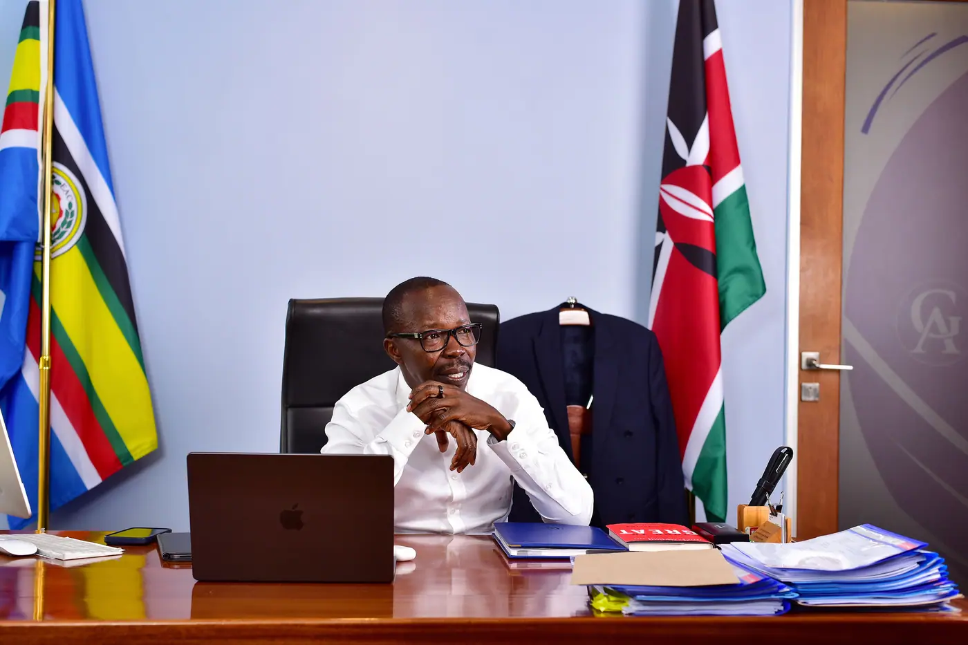 The Managing Partner in his office, flanked by the Kenyan and East African Community flags